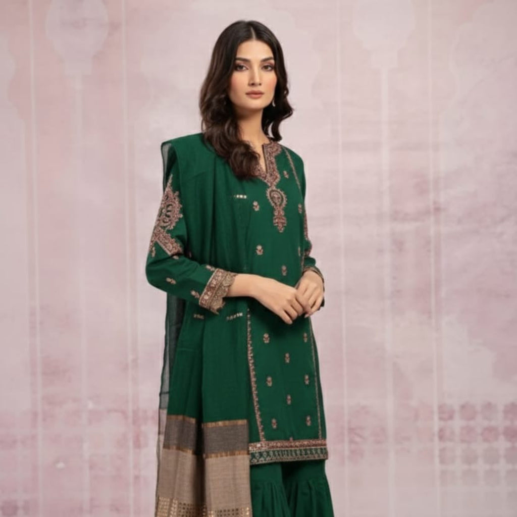 Woman wearing a green traditional outfit with intricate patterns on a light pink background